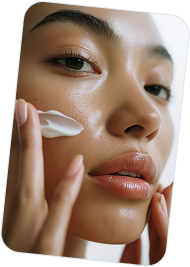 Close-up of a woman applying moisturizer on her cheek with her fingers.